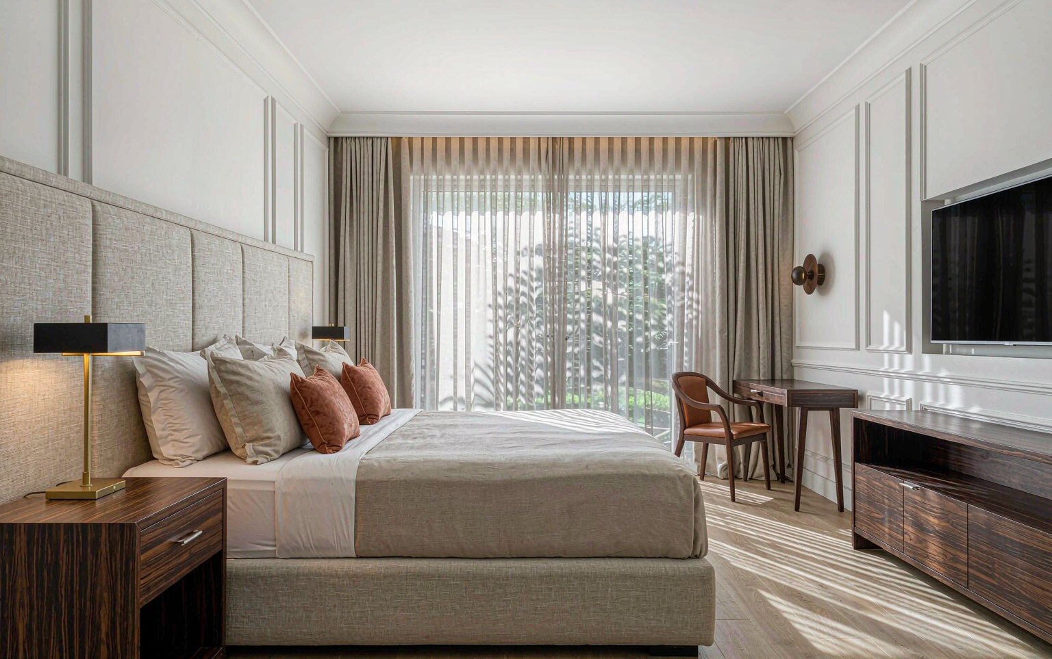 Habitación de hotel con cama King, mesitas de noche y escritorio en madera cálida