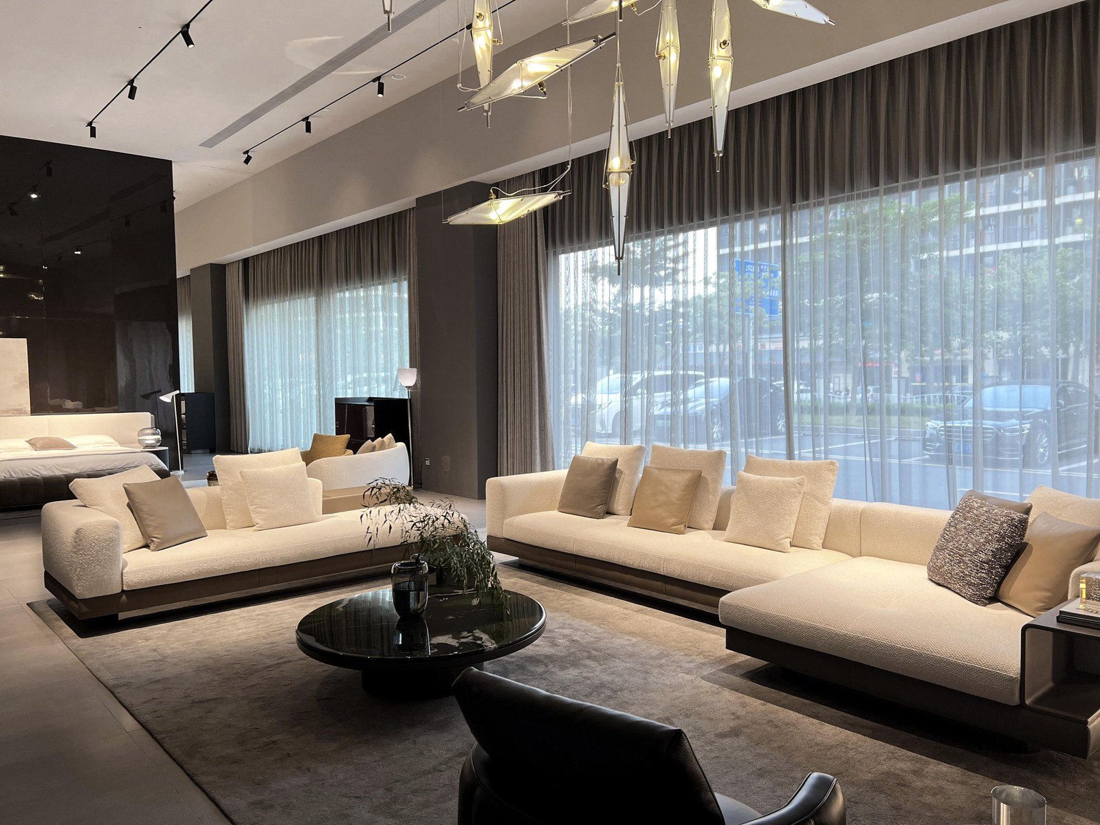 Salón de villa luminoso con sofá modular beige a medida, ventanal de suelo a techo y mesa de centro de piedra.