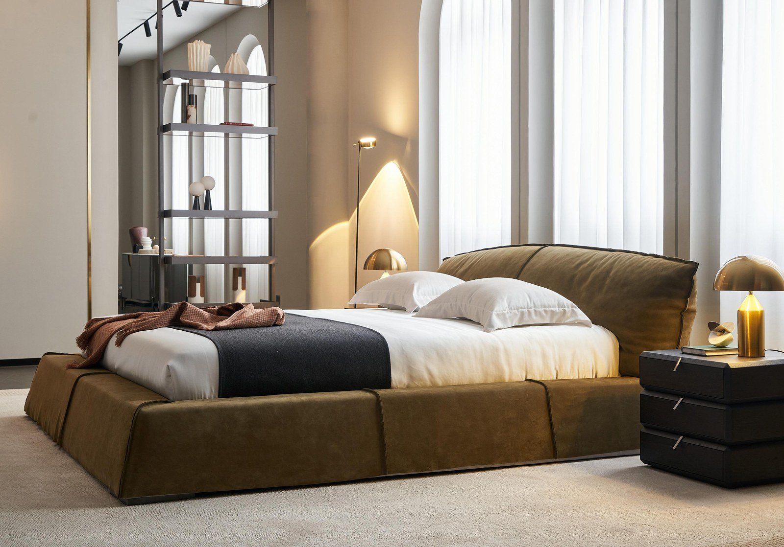 Dormitorio principal con cama baja tapizada en tono oliva y textil en lino dentro de una villa.