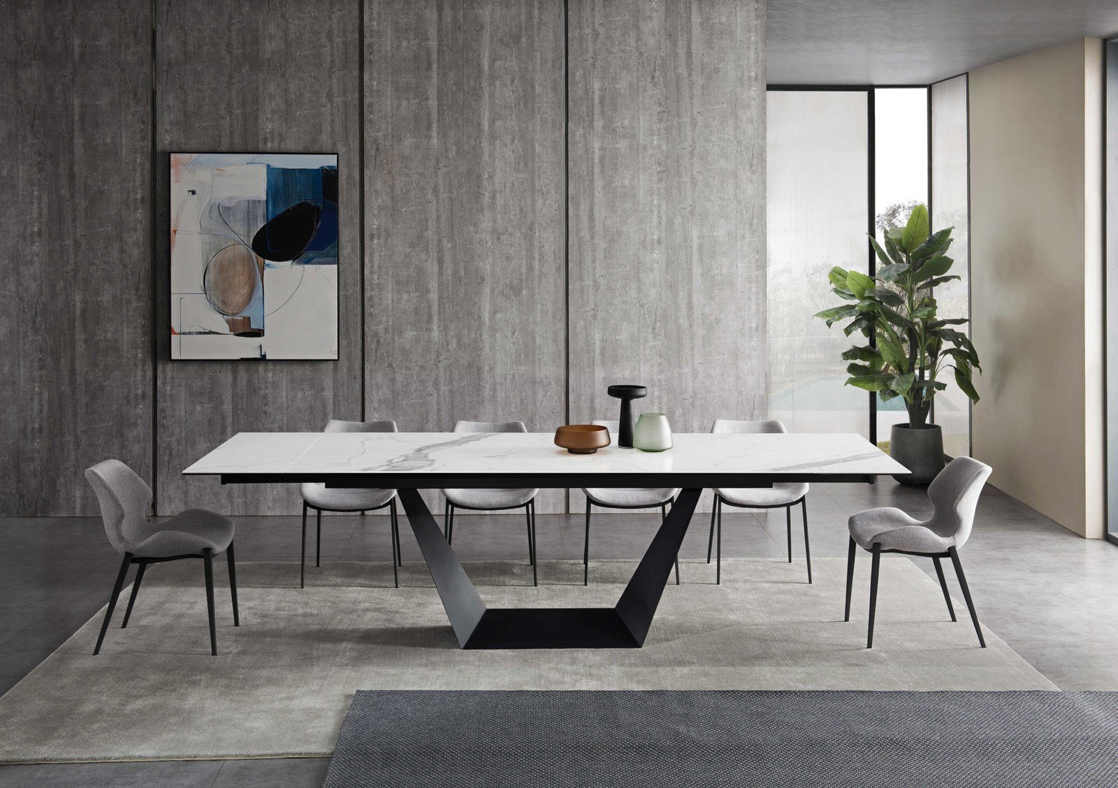 Comedor de villa con mesa de piedra sinterizada a medida, sillas tapizadas en gris y alfombra de lana.