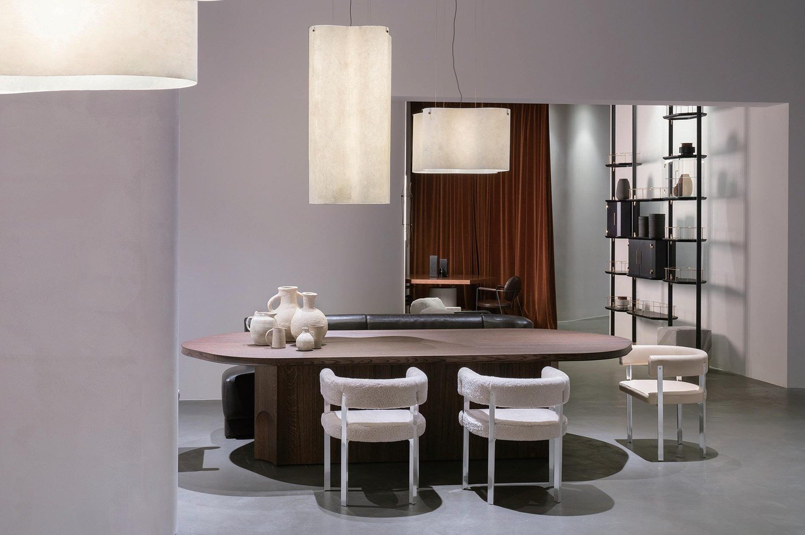 Comedor formal con mesa ovalada de madera, sillas de bouclé y lámparas colgantes de papel.