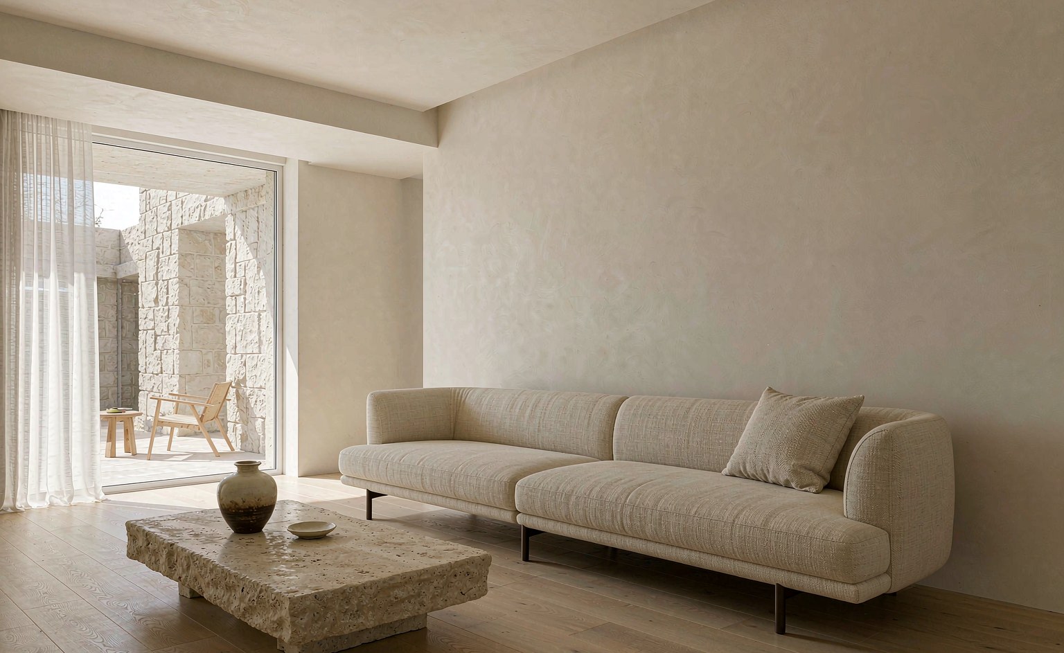 Salón de villa con un sofá a medida de tejido claro junto a una pared lisa y un ventanal lateral