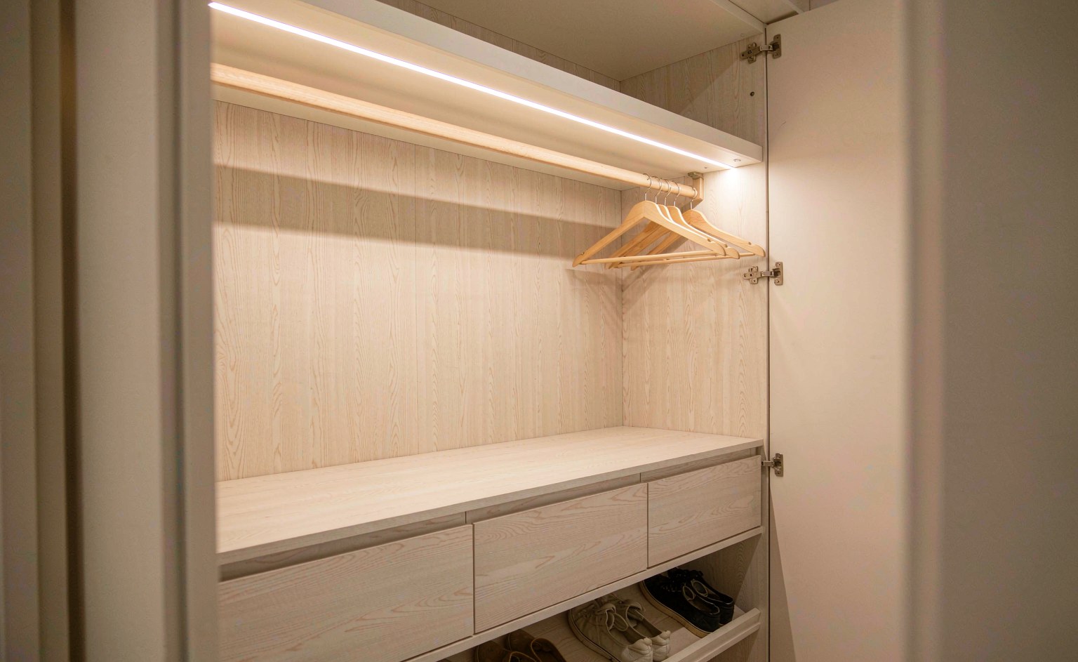 Interior de armario empotrado con iluminación LED cálida integrada bajo los entrepaños