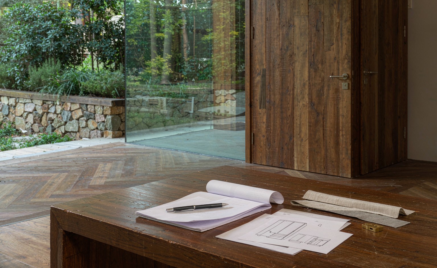 Contrato de muebles a medida con planos y muestras de acabados sobre una mesa de madera en una villa