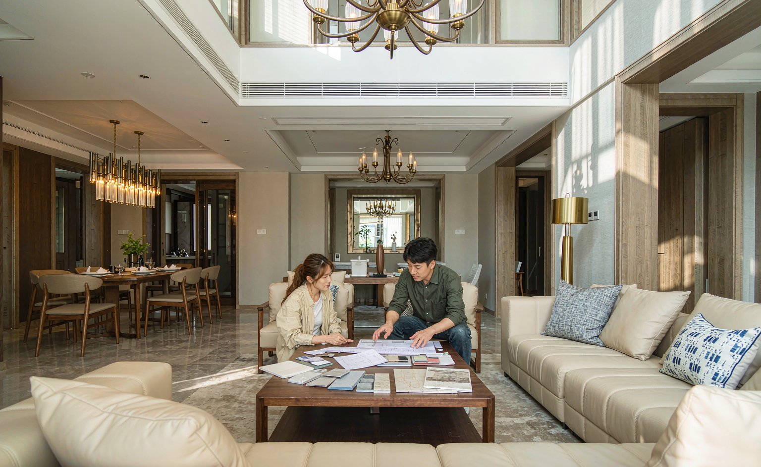 Diseñador de interiores y propietario revisando planos y muestras sobre la mesa de centro de una villa