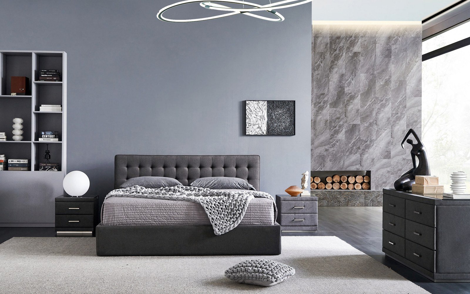 Cama con cabecero capitoné gris y pared de piedra clara en un dormitorio moderno.