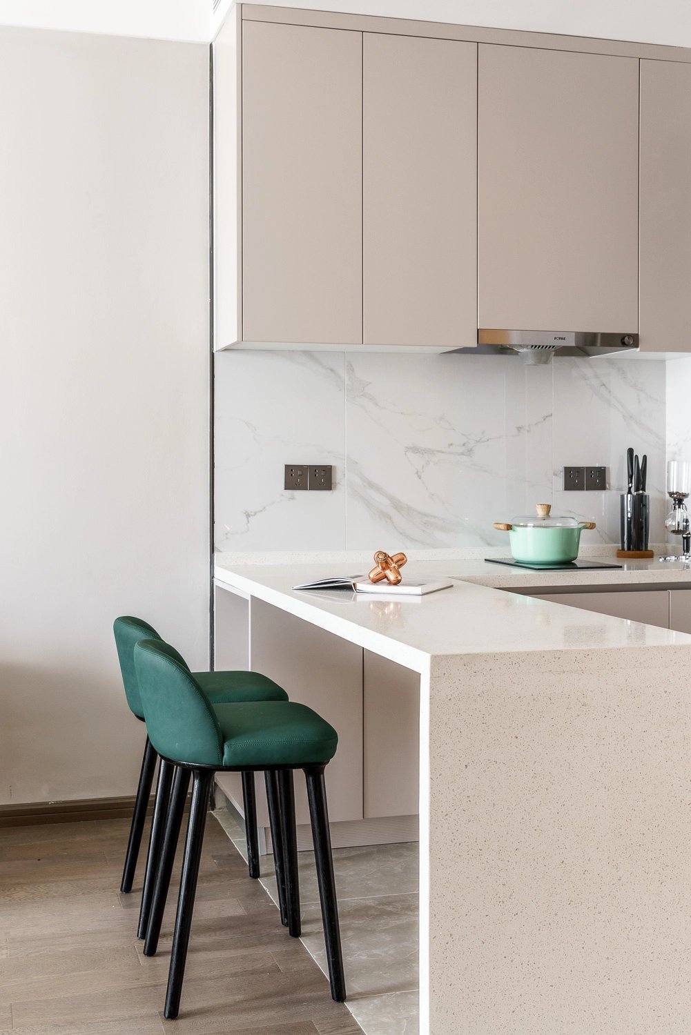 Cocina moderna con barra desayunadora y taburetes verdes en apartamento compacto
