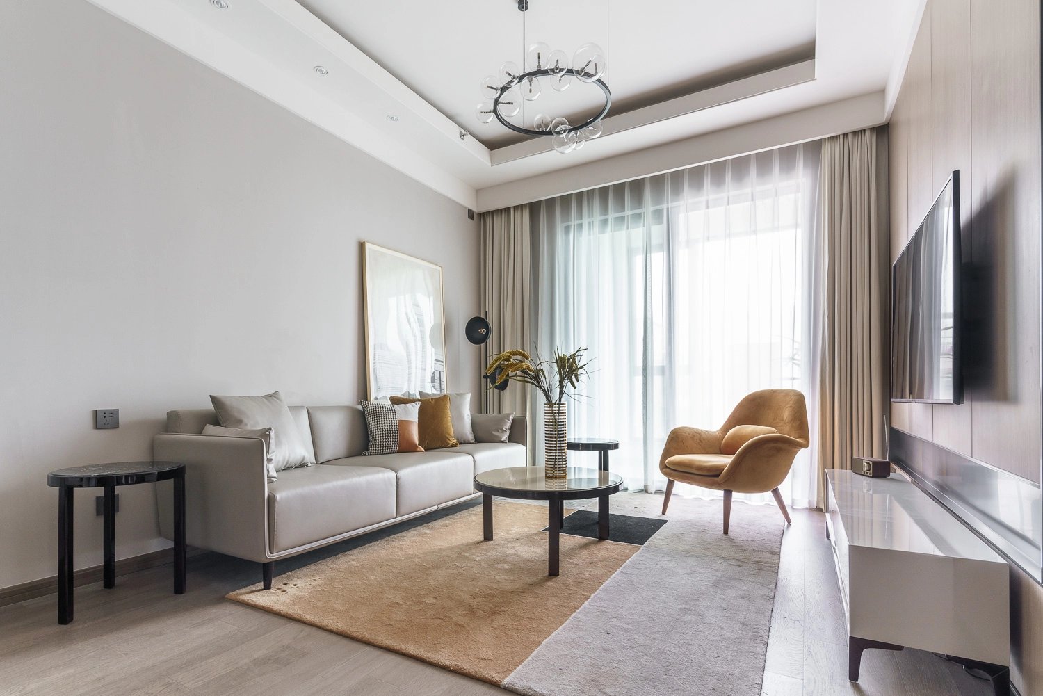 Sala de estar en apartamento pequeño con sofá gris, mesa de centro y butaca junto a ventanal