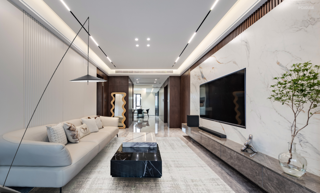 Sala de estar moderna con pared de TV en mármol, sofá blanco y mesa de centro negra