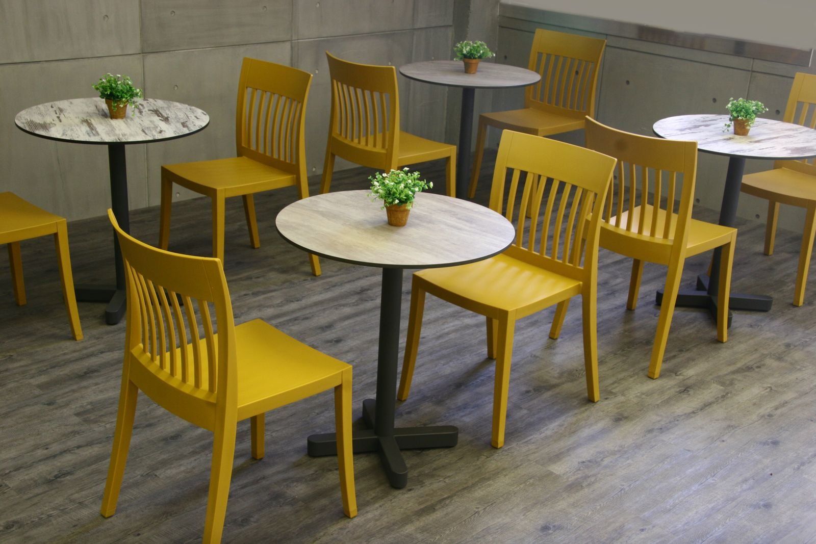 Cafetería moderna con sillas apilables y mesas de mármol en ambiente cálido