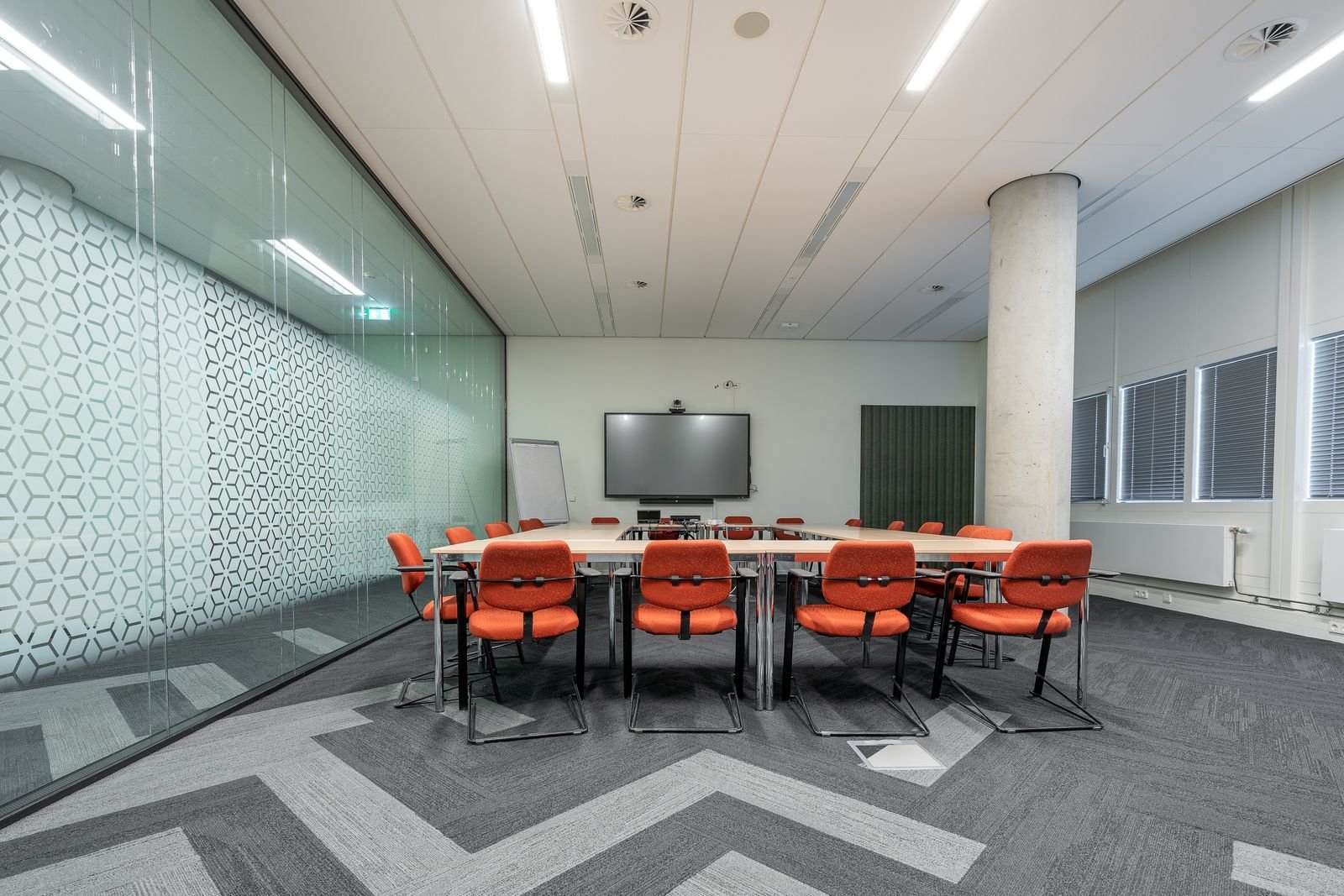 Sala de reuniones moderna con mesa larga y sillas de trineo junto a pantalla